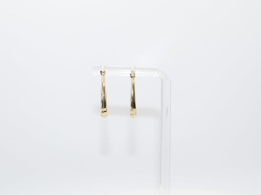 Gold hoop earrings on a clear stand against a white background